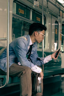 a man sitting on a train looking at his cell phone