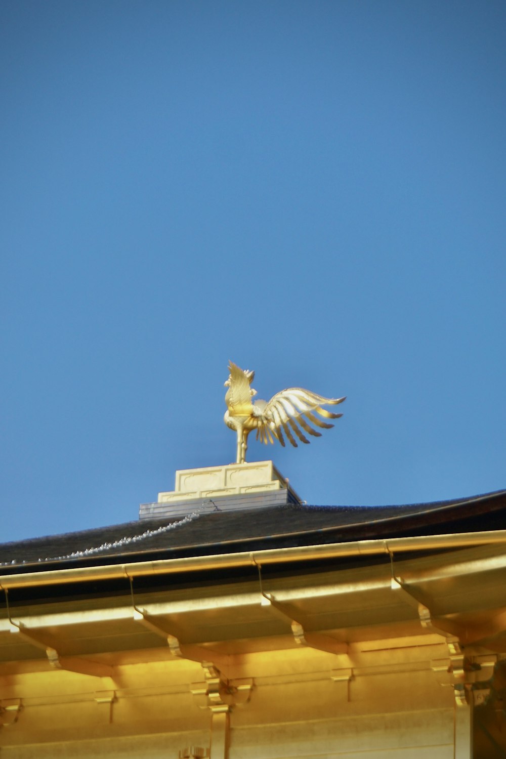 a golden statue of a bird on top of a building