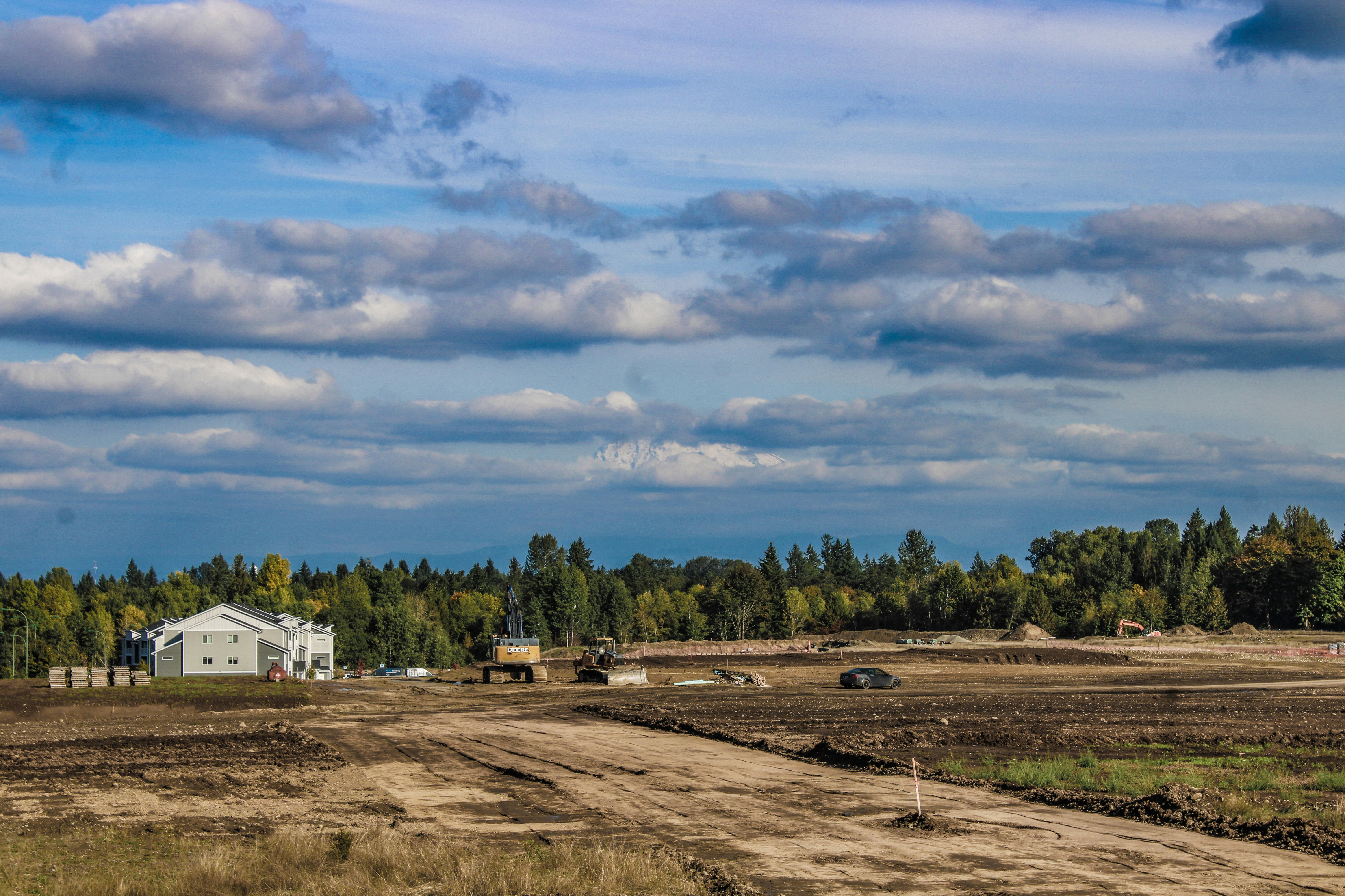 a dirt road in a field with a house in the background