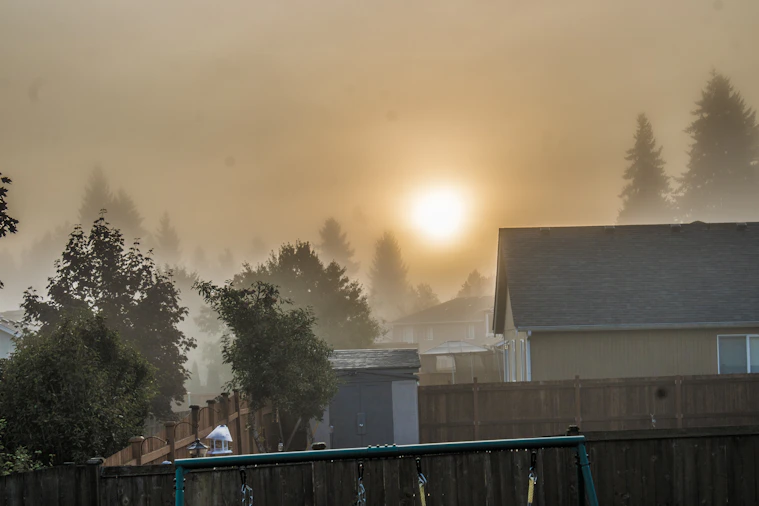the sun is setting over a foggy neighborhood