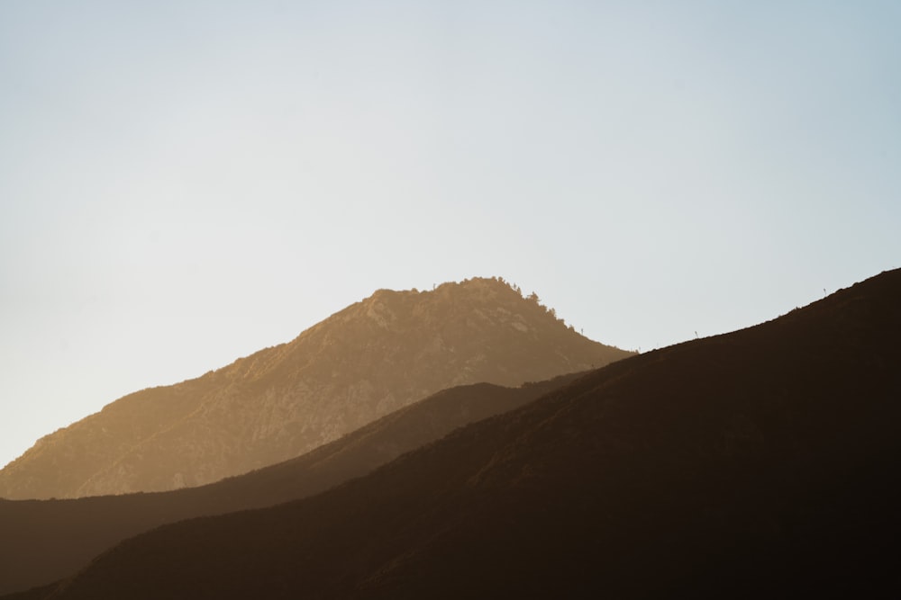 the silhouette of a mountain against a blue sky