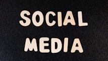Block letters spelling 'SOCIAL MEDIA' arranged on a dark textured background.