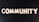 The word 'COMMUNITY' is spelled out with white wooden letters on a dark black background.