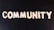 The word 'COMMUNITY' is spelled out with white wooden letters on a dark black background.