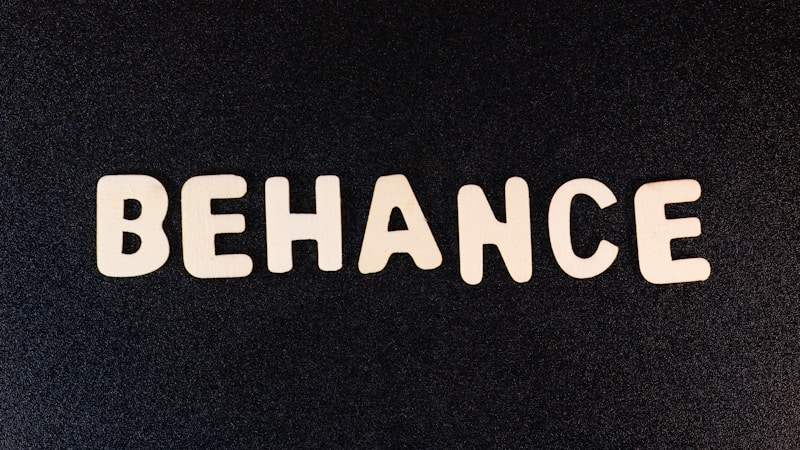 Block letters spelling 'BEHANCE' are arranged on a dark background, appearing in a casual, playful font.