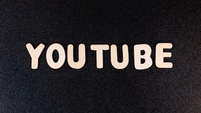 The word 'YOUTUBE' is displayed in white, bold, block letters against a black textured background.