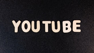The word 'YOUTUBE' is displayed in white, bold, block letters against a black textured background.