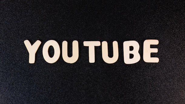 The word 'YOUTUBE' is displayed in white, bold, block letters against a black textured background.