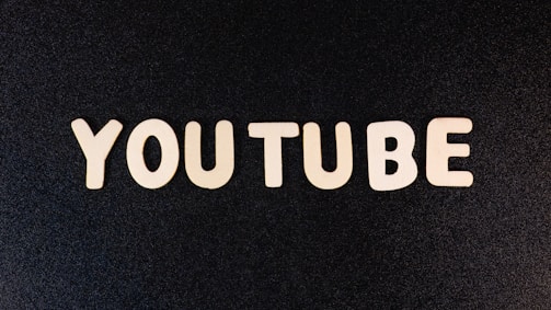 The word 'YOUTUBE' is displayed in white, bold, block letters against a black textured background.