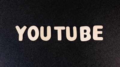 The word 'YOUTUBE' is displayed in white, bold, block letters against a black textured background.