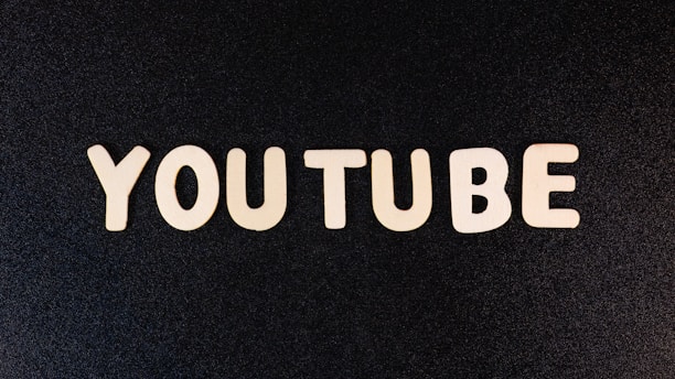 The word 'YOUTUBE' is displayed in white, bold, block letters against a black textured background.