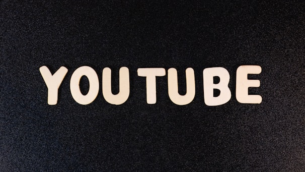 The word 'YOUTUBE' is displayed in white, bold, block letters against a black textured background.