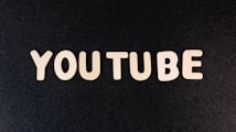 The word 'YOUTUBE' is displayed in white, bold, block letters against a black textured background.