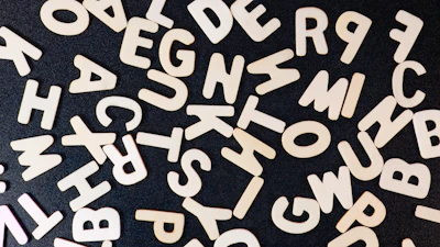 Close-up of small hands arranging wooden letters on a soft linen mat.