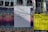 A wall covered with various street art and event posters, including a central white poster with handwritten text that reads 'THIS IS THE RECORD OF THE TIME.' The surrounding posters feature colorful designs with details of events and artists, including Carl Craig's event in black text on a bright yellow background.