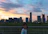 A smiling young traveler standing in front of a futuristic Shenzhen skyline at sunset.