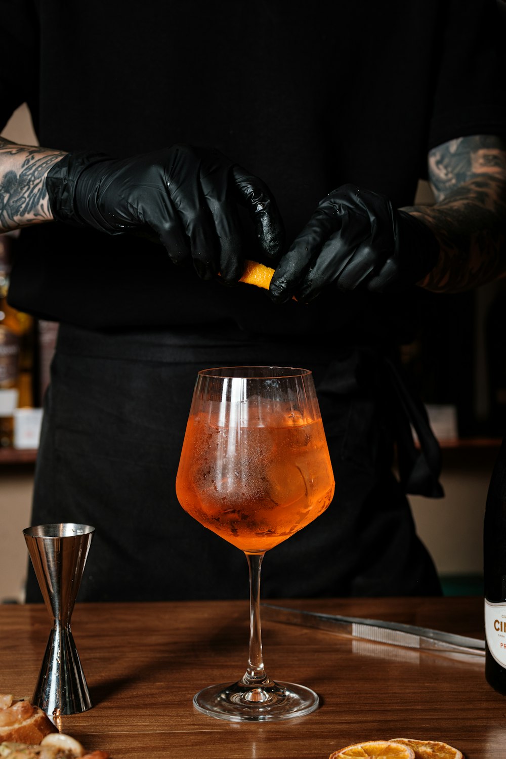 a person in a black shirt and black gloves is making a drink