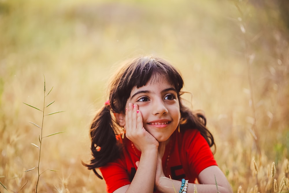 a little girl laying in a field of tall grass