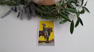 The Two of Pentacles card resting on a velvet cloth with subtle golden sparkles around it.