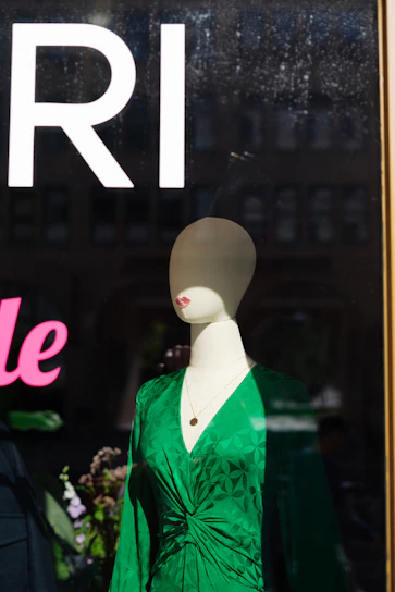 A vibrant green sundress displayed on a mannequin against a soft white background.