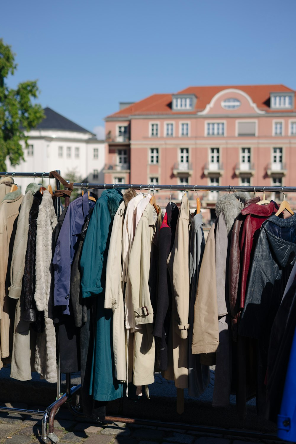 a rack of coats and jackets in front of a building