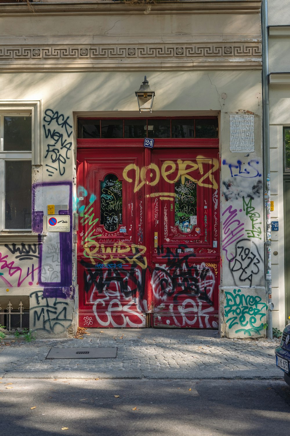 a car parked in front of a red door covered in graffiti