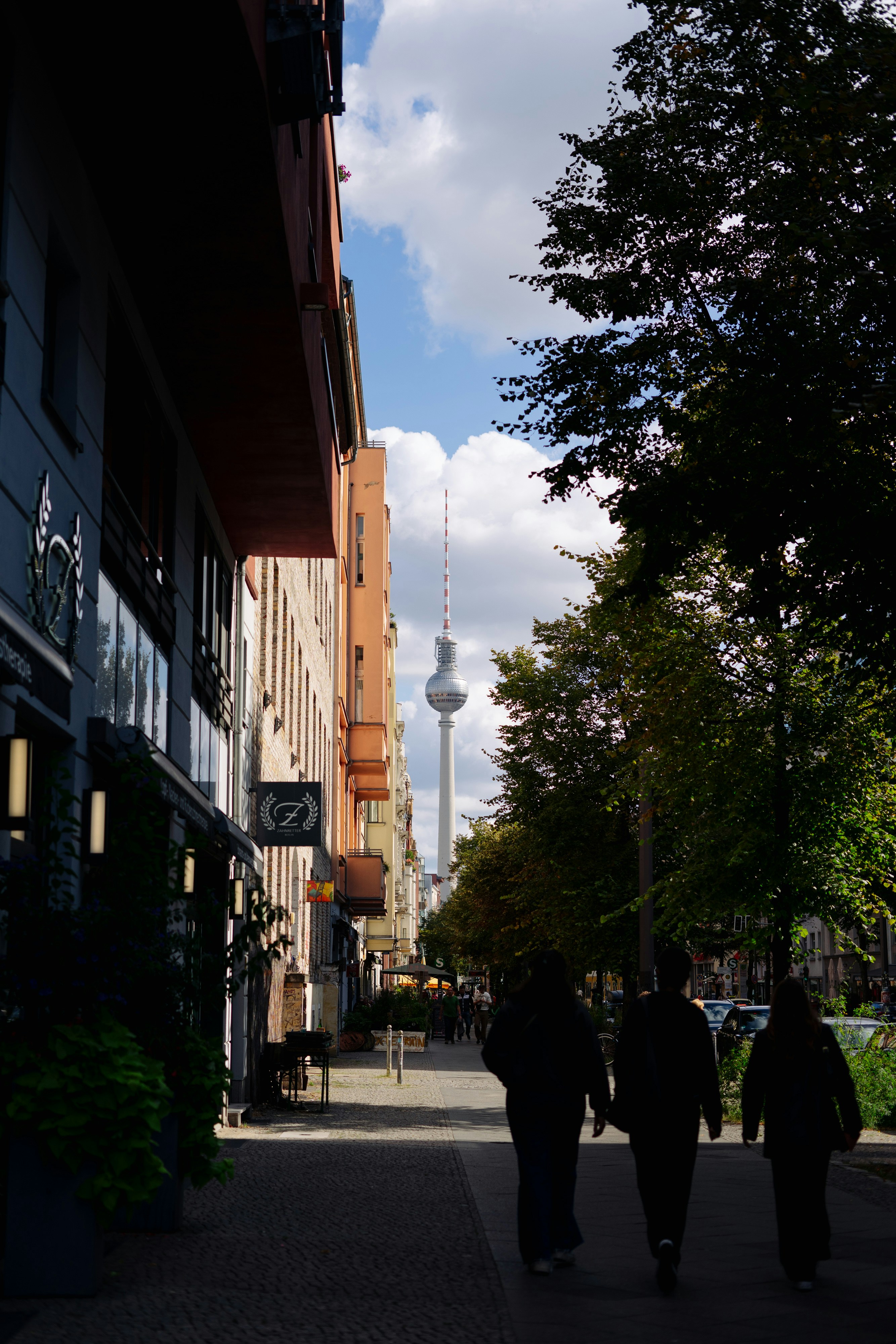 a couple of people walking down a street next to tall buildings