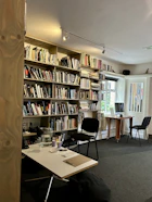 A warmly lit study room filled with open books, a laptop, and notes scattered across a wooden desk.