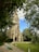 A warm, inviting photo of the church entrance with sunlight filtering through nearby trees.