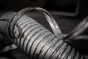 Close-up of tightly coiled galvanized iron wire with metallic sheen under industrial lighting