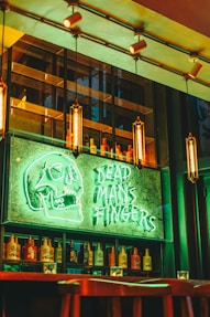 a bar with a neon sign that says dead man's fingers