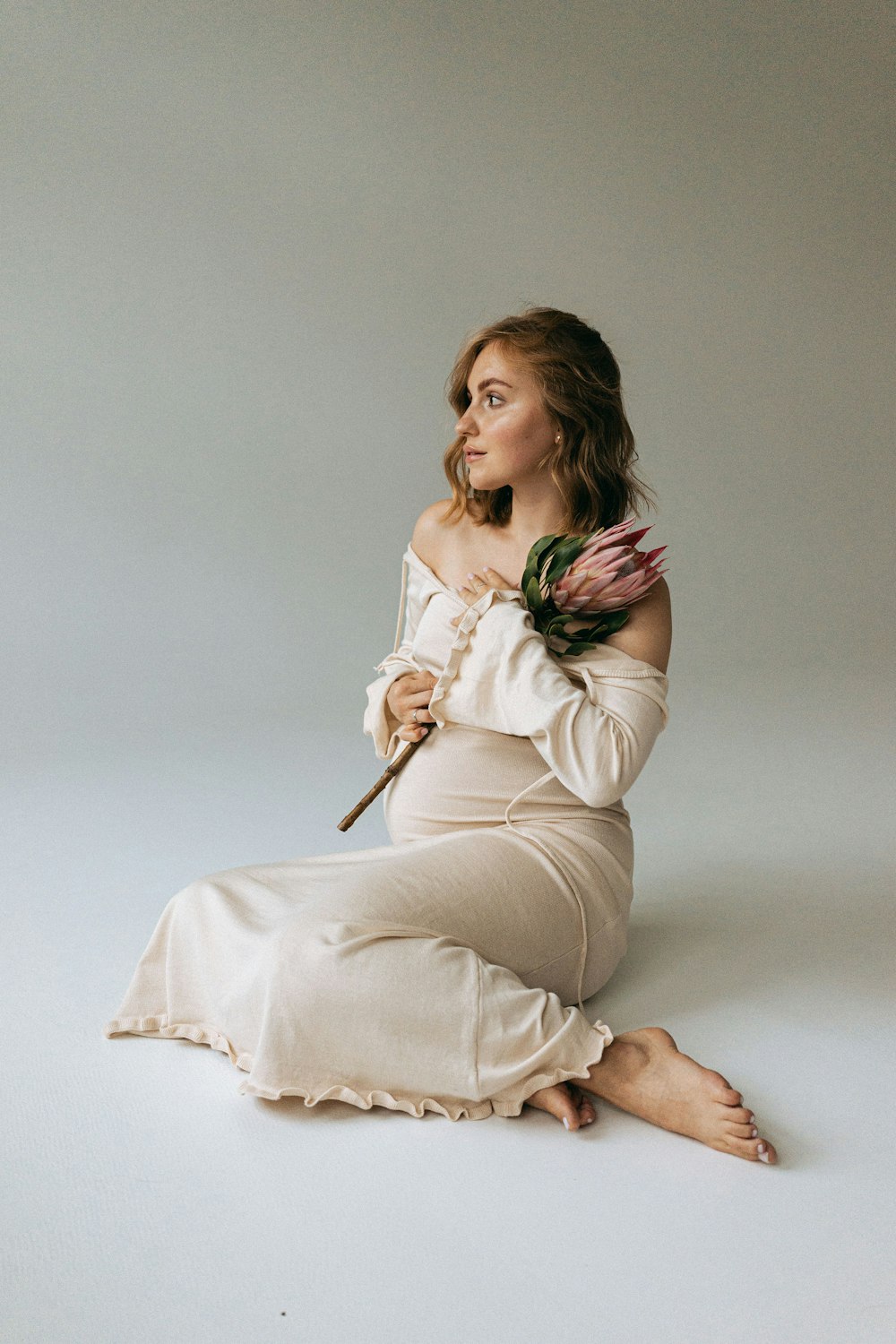 a woman sitting on the ground holding a flower