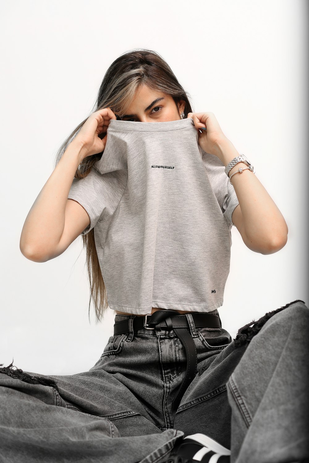 a woman sitting on the floor holding a t - shirt over her face