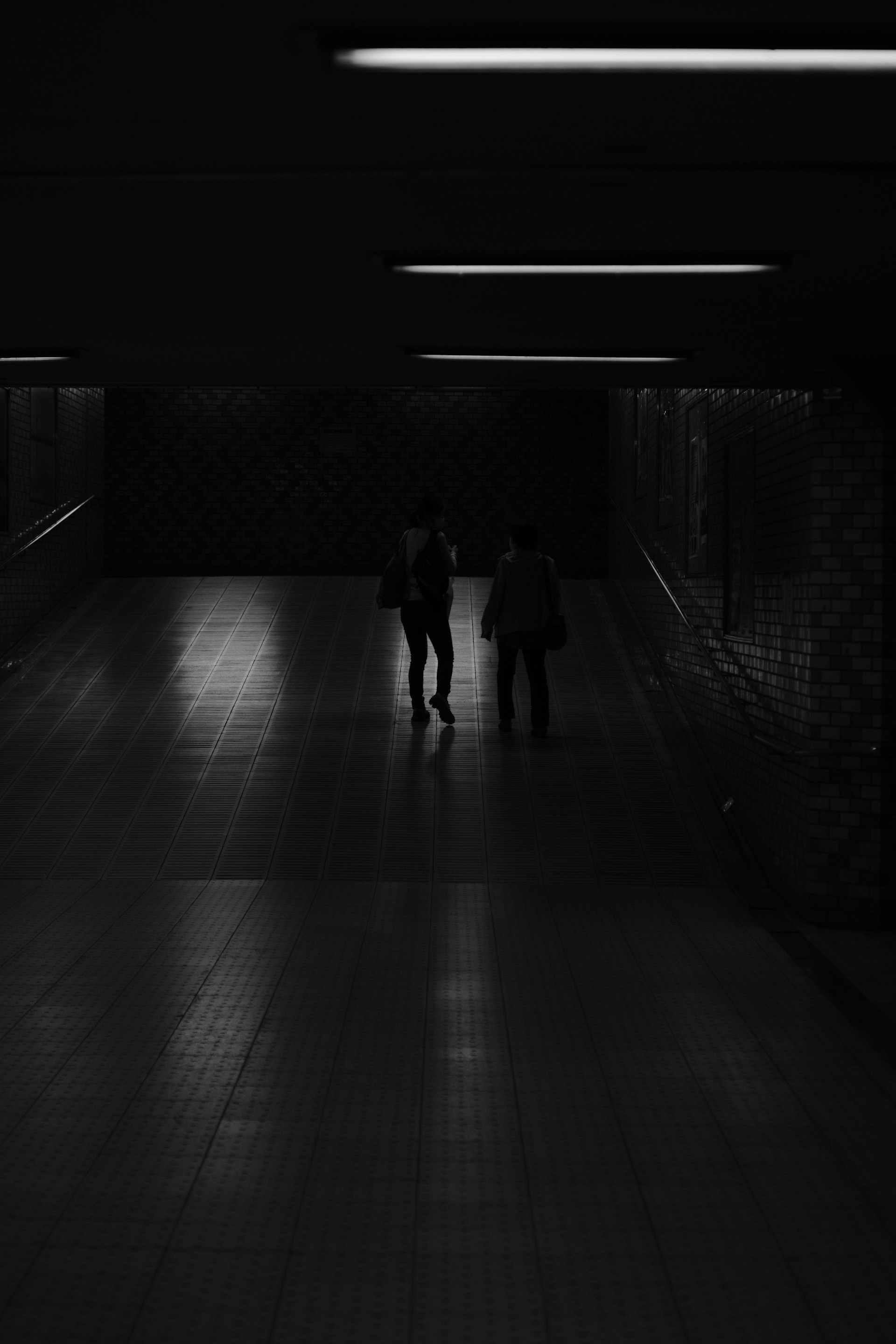 a couple of people walking down a dark hallway