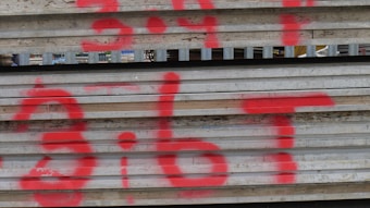 Corrugated metal sheets with red spray-painted markings. The surface appears rusted and weathered, suggesting it is part of a construction site or industrial area.