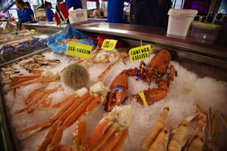 A friendly customer service representative smiling beside a fresh seafood display.