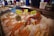 A display of fresh seafood on ice, including crab legs, a giant wild lobster, and a sea urchin. The seafood is labeled with bright yellow signs, and a Norwegian flag is visible in the background. People in blue uniforms are seen behind the counter.