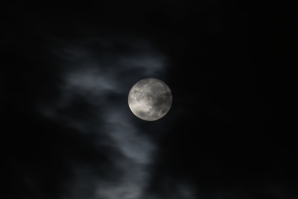 Una luna llena en el cielo oscuro con nubes