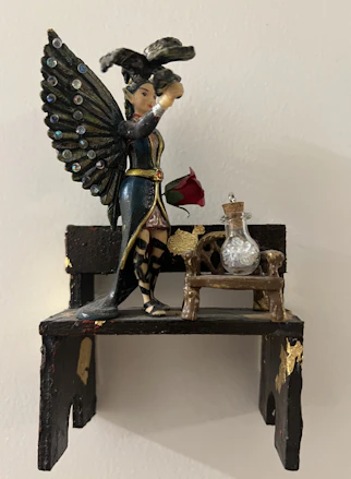 A beautifully painted resin sculpture of a classic home decor item on a wooden shelf.