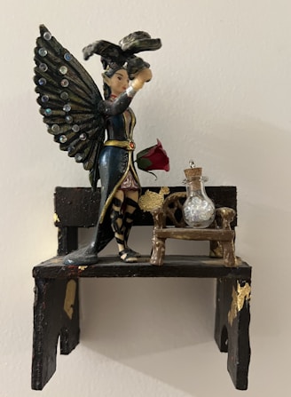 A beautifully painted resin sculpture of a classic home decor item on a wooden shelf.