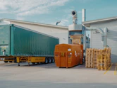 a semi truck is parked in front of a warehouse