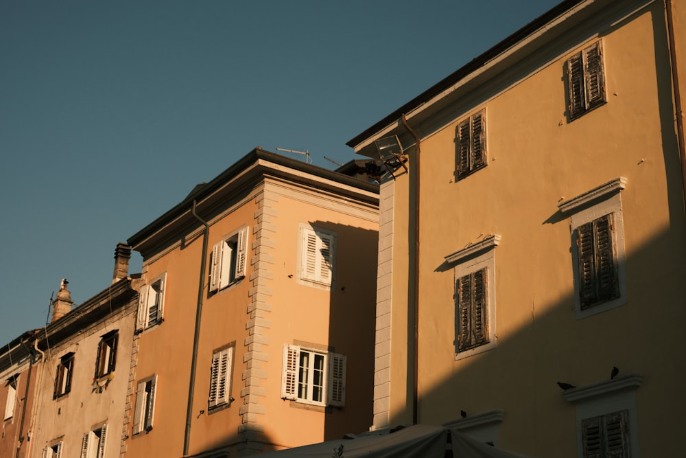 a yellow building with white windows and shutters