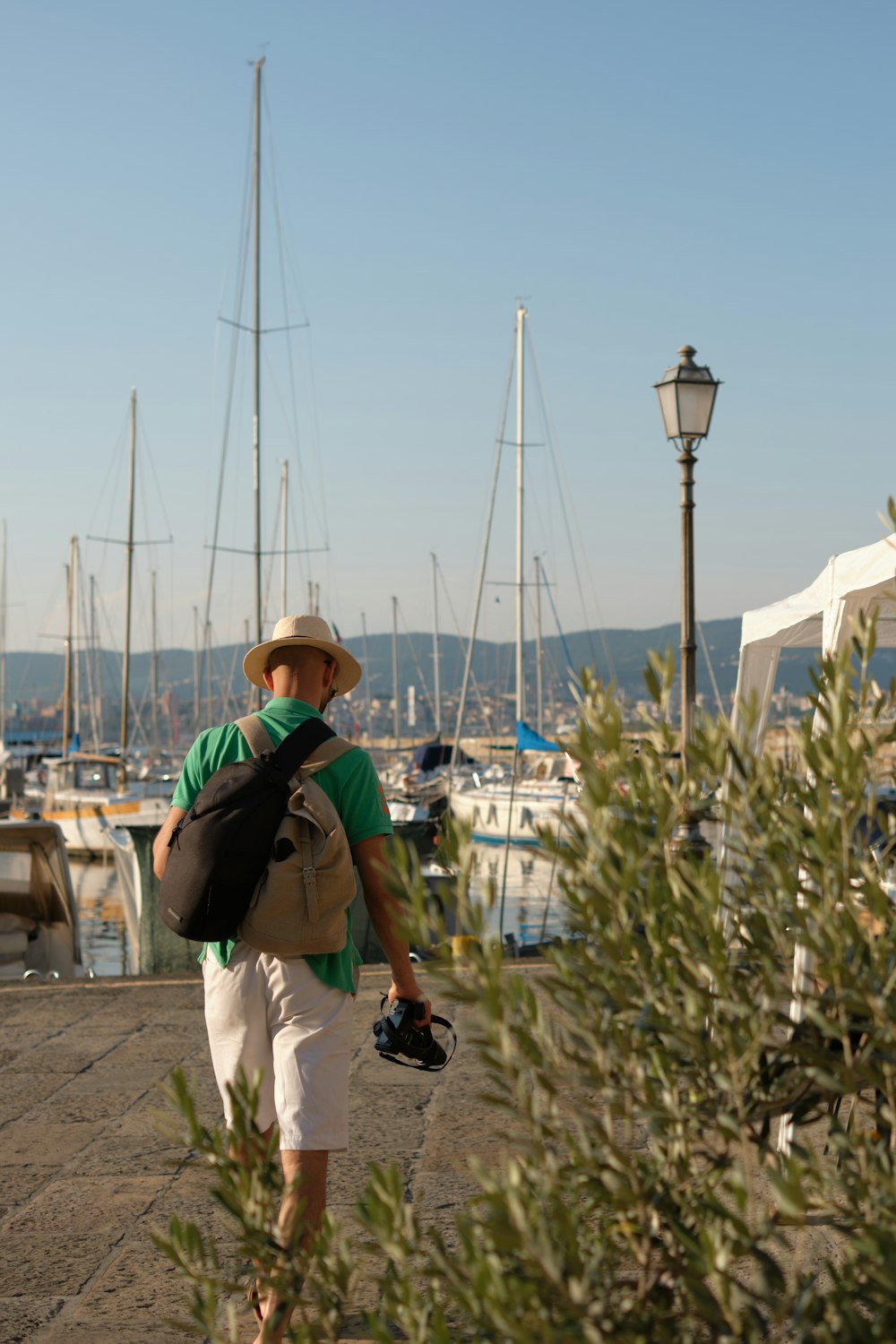 a man with a backpack and a camera walking towards a marina