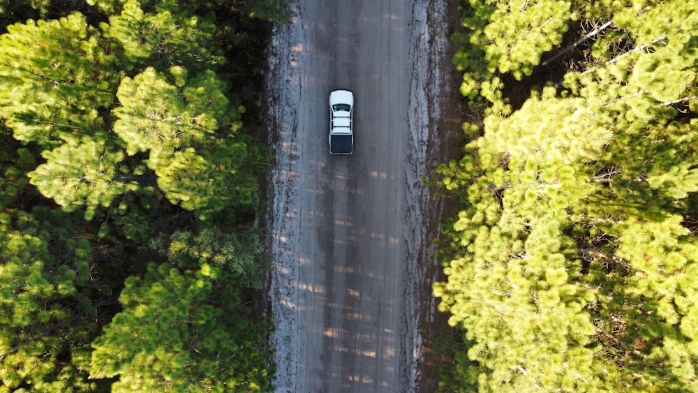 an aerial view of a car driving through a forest