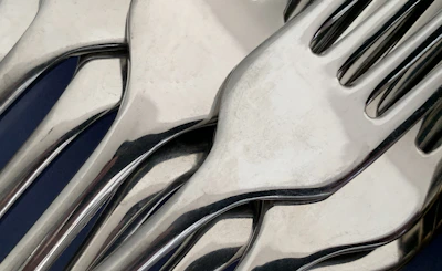 Close-up of high-quality forks, spoons, and knives with a professional blue background.