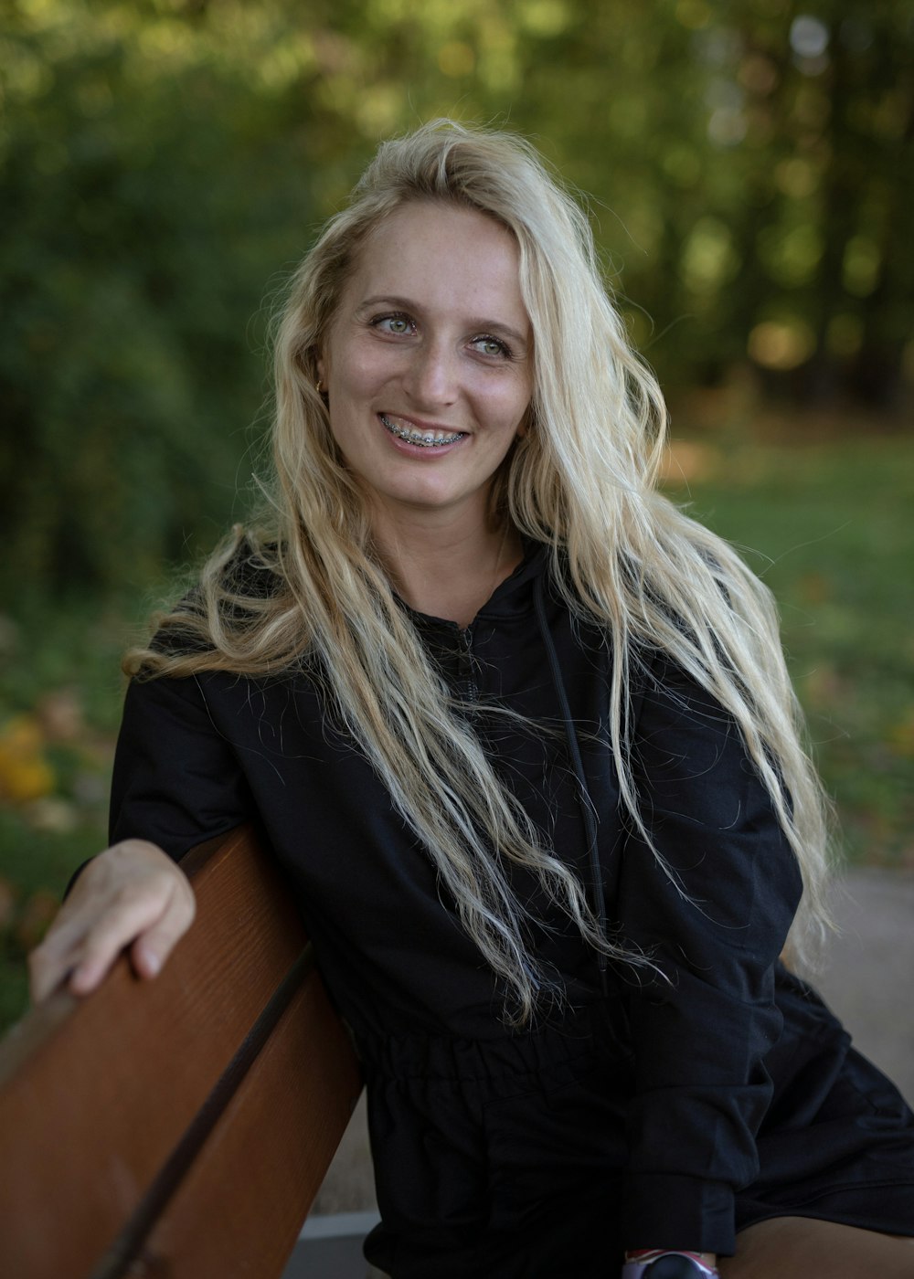 a woman with long blonde hair sitting on a bench