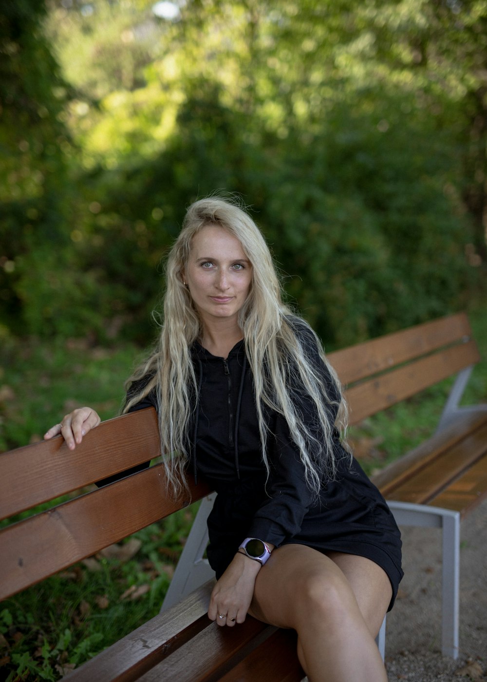 a woman sitting on a wooden bench in a park