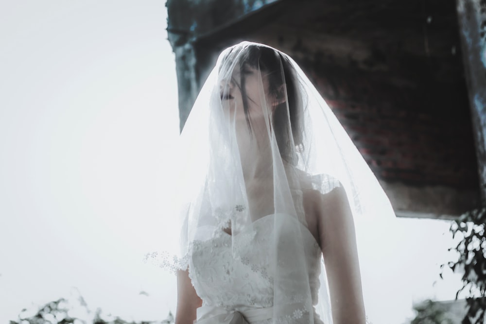 a woman in a wedding dress with a veil over her head