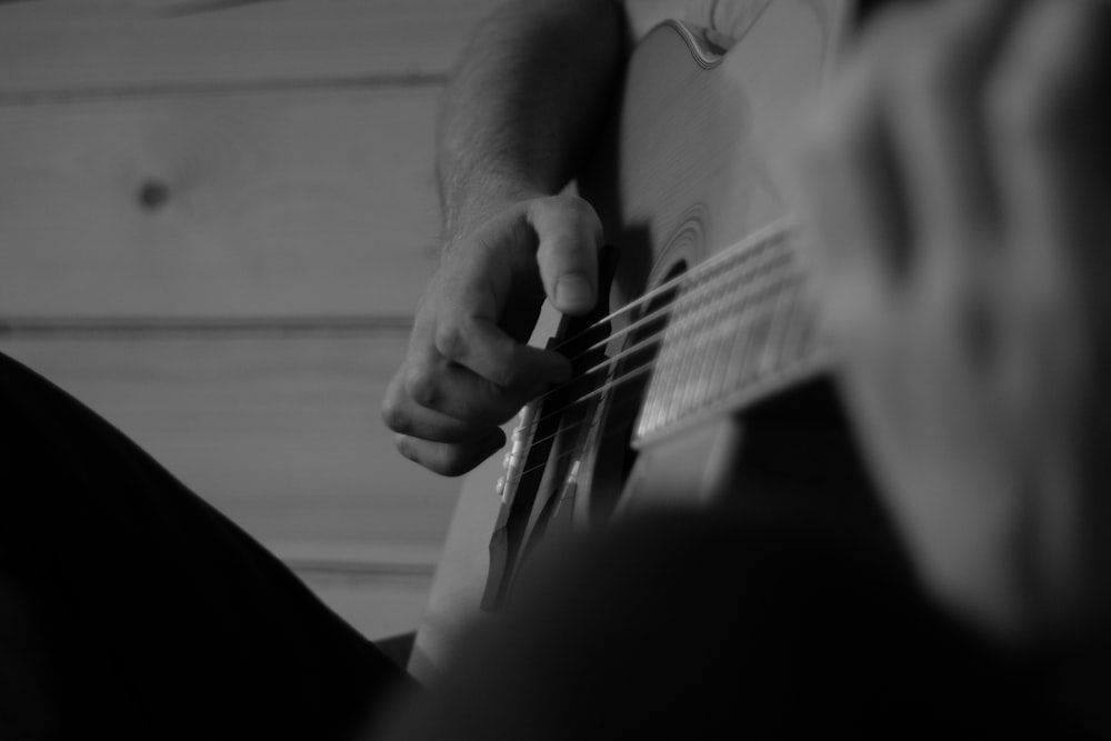 a black and white photo of a person playing a guitar