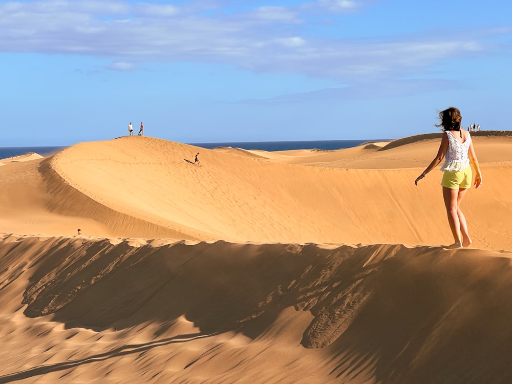 a woman standing on top of a sand dune